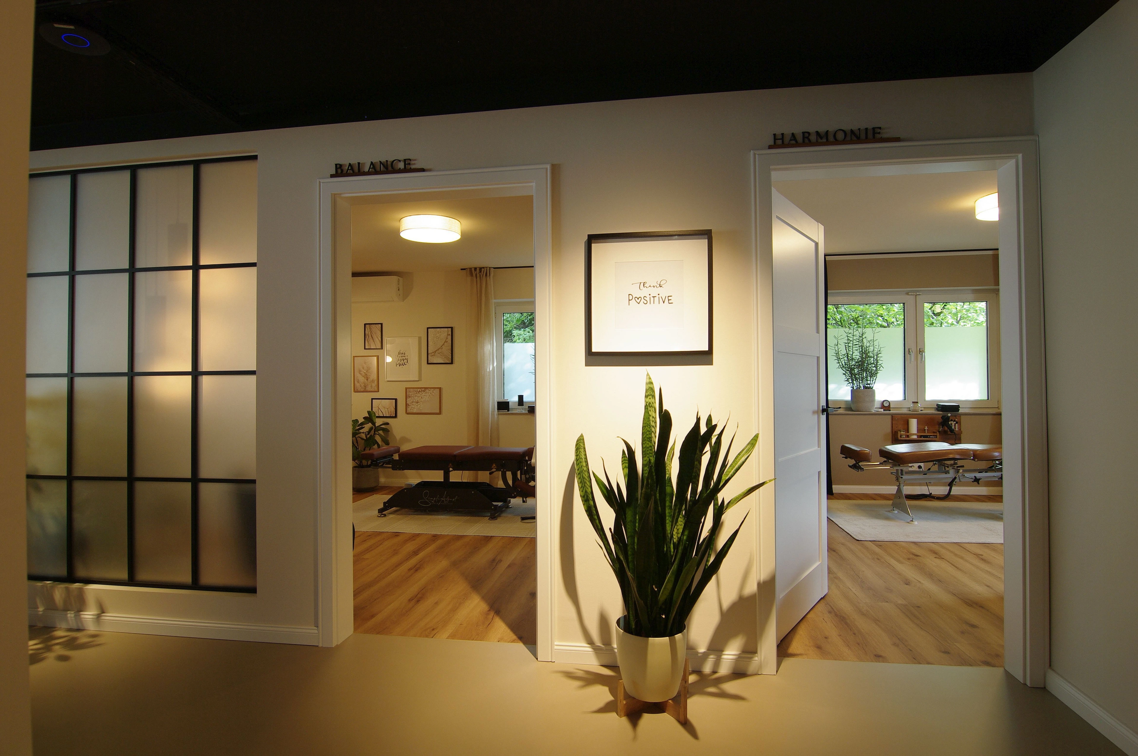 Erschaffung einer Praxis mit Schwerpunkt auf Chirotherapie — Blick in zwei Behandlungsräume der Chiropraxis mit Therapieliegen und Holzfußboden — Praxisumbau von Bernd Schüller