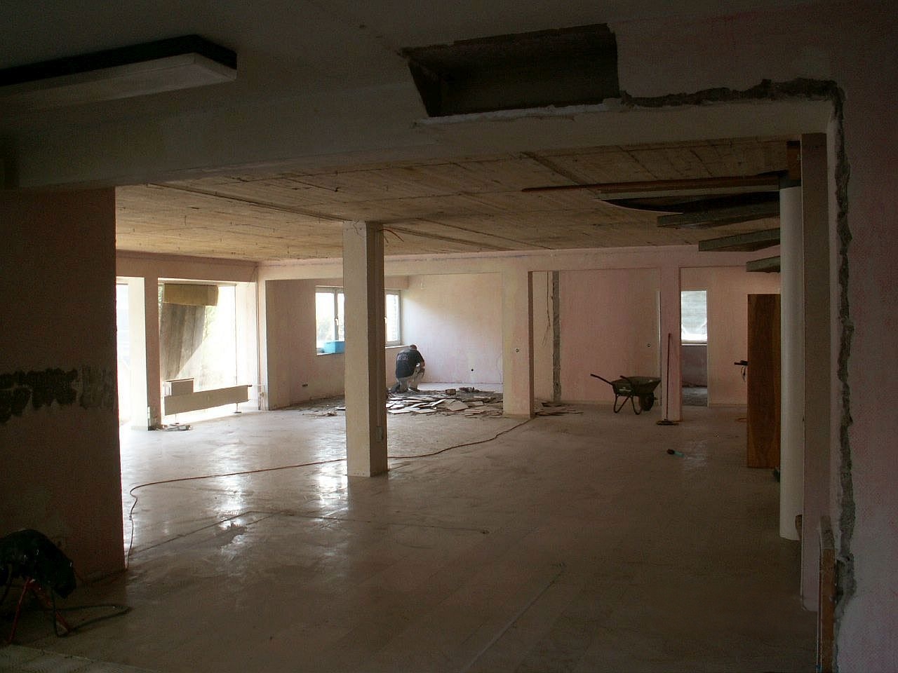 Blick durch einen offenen Wanddurchbruch auf die entkernte Büroetage vor dem Praxisumbau