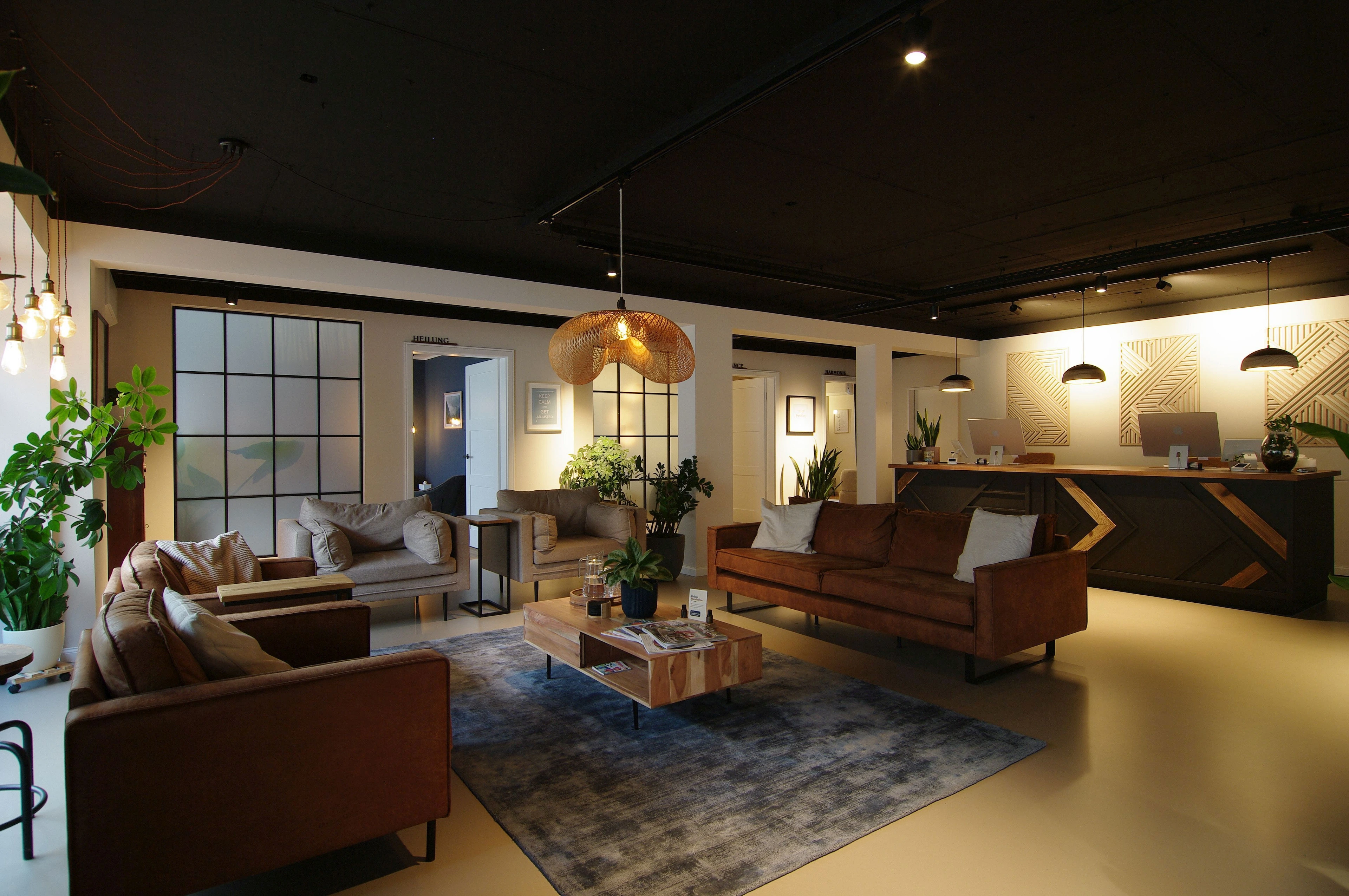 Erschaffung einer Praxis mit Schwerpunkt auf Chirotherapie — Wartebereich mit Sofas, Holztisch und Blick auf die Rezeption der Chiropraxis — Praxisumbau von Bernd Schüller