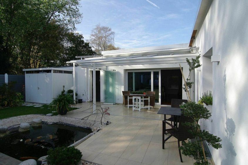 Umbau eines Bungalows, Duisburg-Rahm — Terrasse mit Pergola, Sitzgruppe und Teich im begrünten Garten des Bungalows
