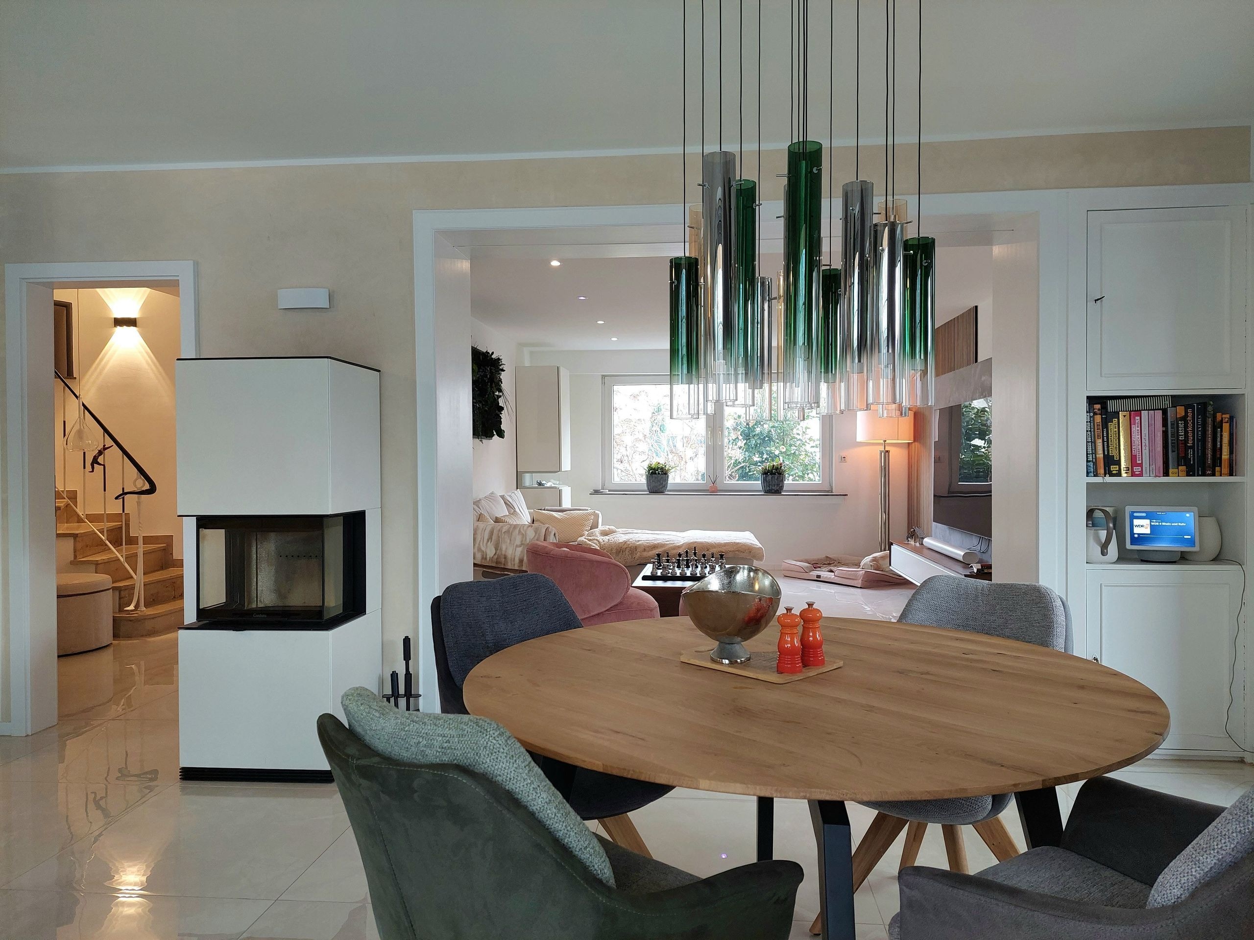 Ess- und Wohnraum mit rundem Holztisch, Glasleuchten und weißem Kamin in Langenfeld — Innenarchitektur von Bernd Schüller
